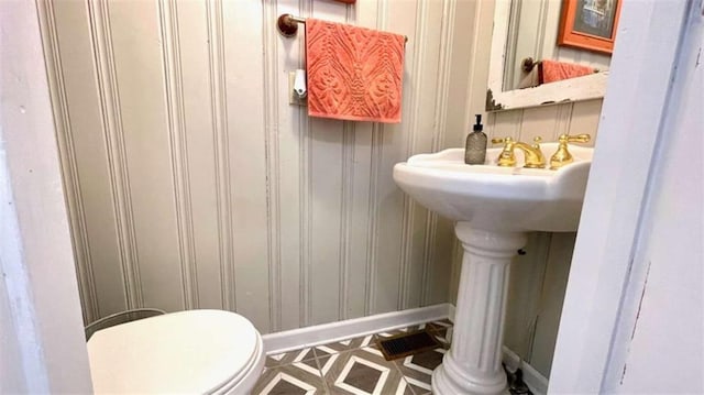 bathroom with baseboards, toilet, and a sink