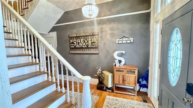 foyer featuring wood finished floors, stairs, a chandelier, and baseboards