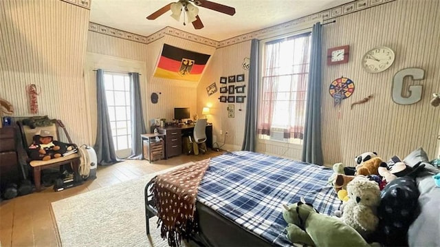 bedroom featuring wallpapered walls, multiple windows, an office area, and wood finished floors