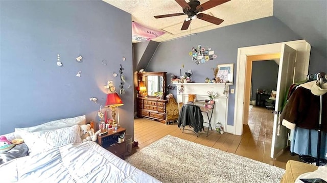 bedroom with hardwood / wood-style floors, lofted ceiling, ceiling fan, and a textured ceiling