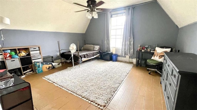 bedroom with lofted ceiling, wood finished floors, a textured ceiling, and a ceiling fan