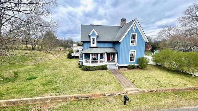 view of front of home featuring covered porch, roof with shingles, a chimney, and a front lawn