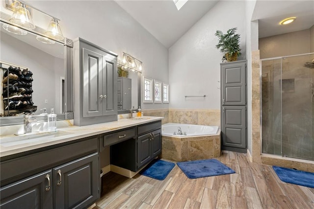 full bath featuring lofted ceiling, wood finished floors, a sink, a shower stall, and a bath