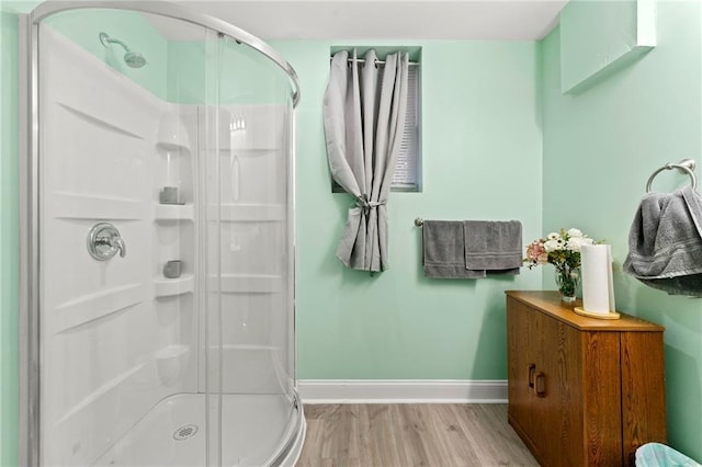 bathroom featuring a shower stall, baseboards, and wood finished floors