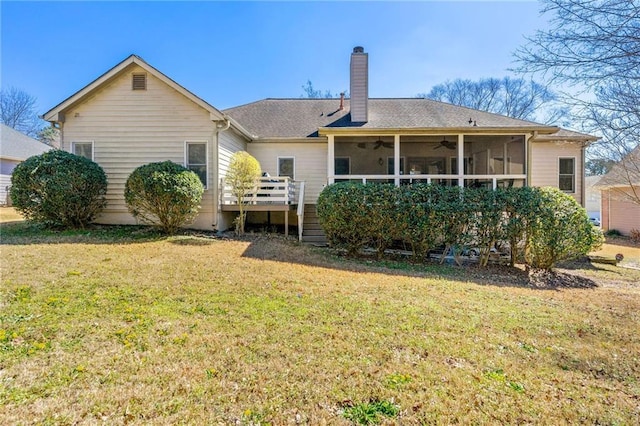 back of property featuring a chimney, a lawn, a ceiling fan, a sunroom, and a wooden deck