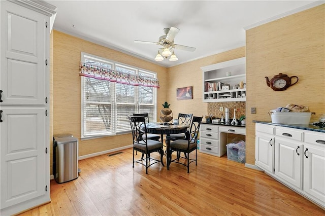 dining room featuring ceiling fan, visible vents, baseboards, light wood-type flooring, and crown molding