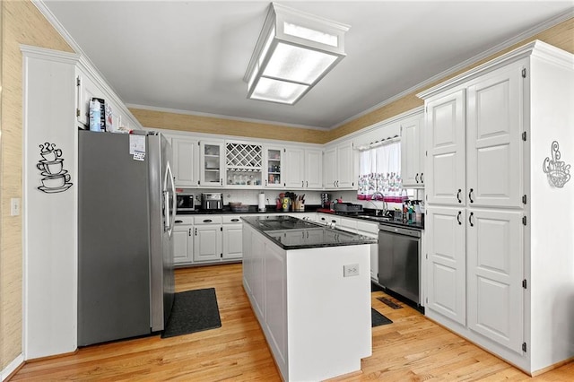 kitchen with a sink, white cabinetry, light wood-style floors, appliances with stainless steel finishes, and crown molding