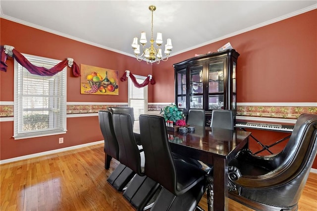 dining space with ornamental molding, wainscoting, wood finished floors, and an inviting chandelier