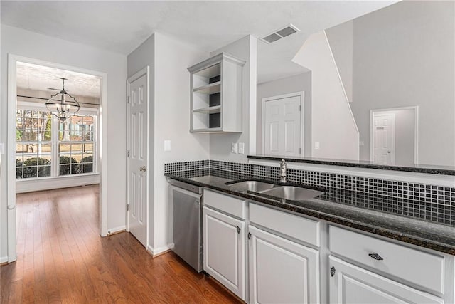 kitchen with a sink, visible vents, dishwasher, and dark stone countertops