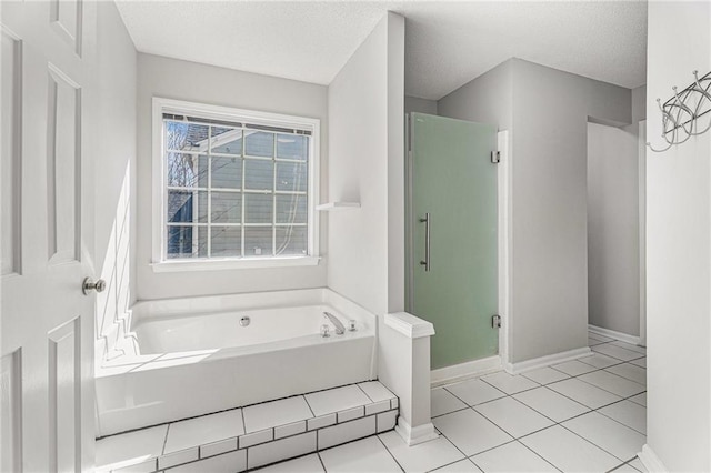 bathroom featuring tile patterned floors, a bath, baseboards, and a stall shower