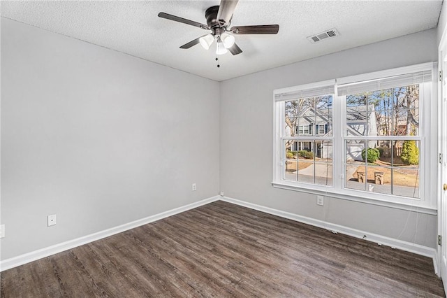 unfurnished room with visible vents, baseboards, dark wood-style floors, a textured ceiling, and a ceiling fan