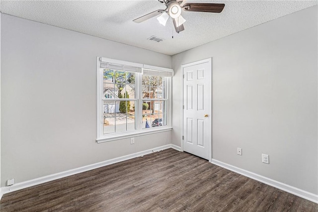 empty room with a ceiling fan, visible vents, baseboards, dark wood-style flooring, and a textured ceiling