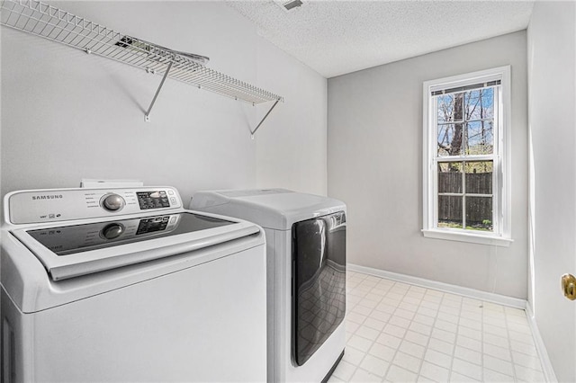 clothes washing area featuring laundry area, baseboards, independent washer and dryer, and a textured ceiling