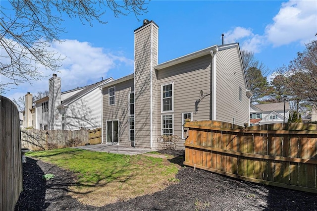 back of house featuring a patio, a lawn, fence private yard, and a chimney