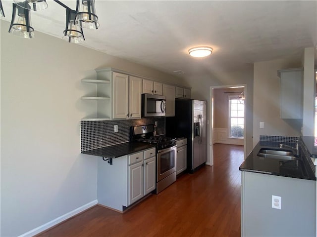 kitchen with dark countertops, open shelves, appliances with stainless steel finishes, and a sink