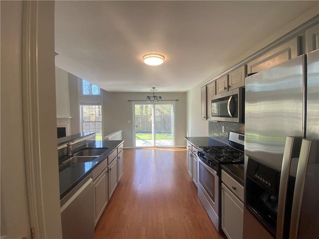 kitchen with dark countertops, wood finished floors, backsplash, and stainless steel appliances