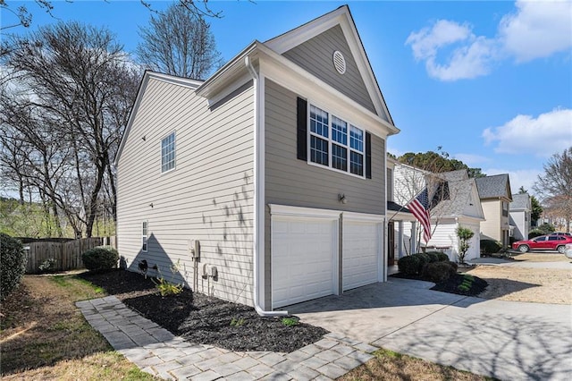 view of side of home with driveway, a garage, and fence