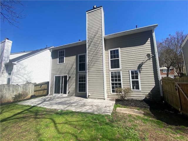 rear view of house featuring a lawn, a chimney, a patio, and fence