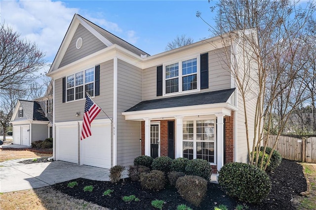 traditional home featuring a garage, brick siding, concrete driveway, and fence