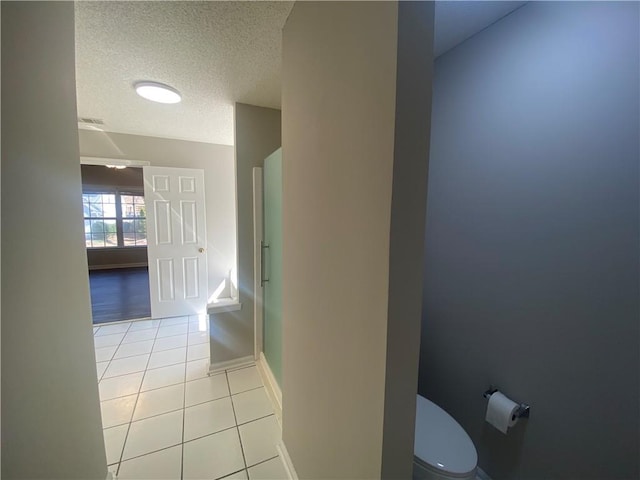 bathroom featuring baseboards, visible vents, a textured ceiling, tile patterned floors, and toilet