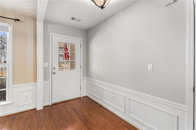 doorway featuring visible vents, dark wood-type flooring, and a wainscoted wall