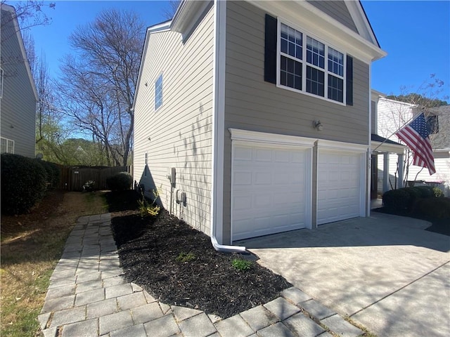 view of home's exterior featuring a garage, concrete driveway, and fence