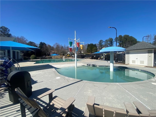 community pool with an outdoor structure and a patio area