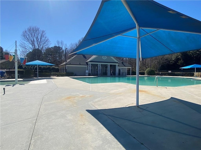 pool with a patio, an outdoor structure, and fence