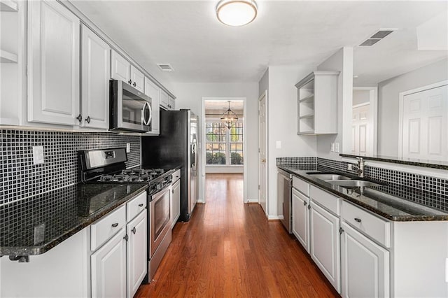 kitchen with a sink, appliances with stainless steel finishes, decorative backsplash, and open shelves