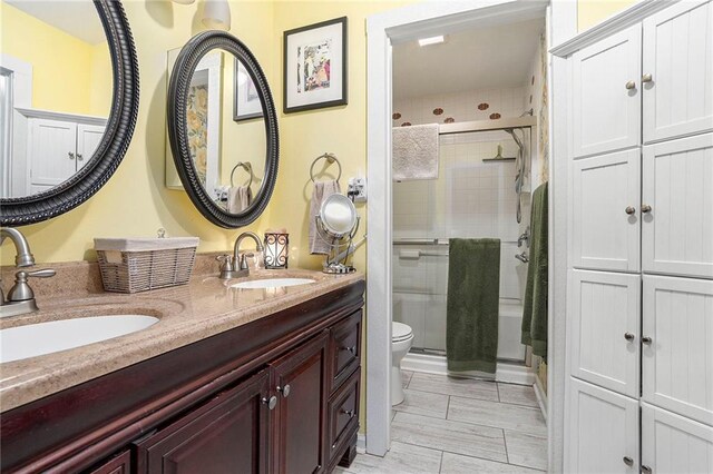 bathroom featuring dual vanity and toilet