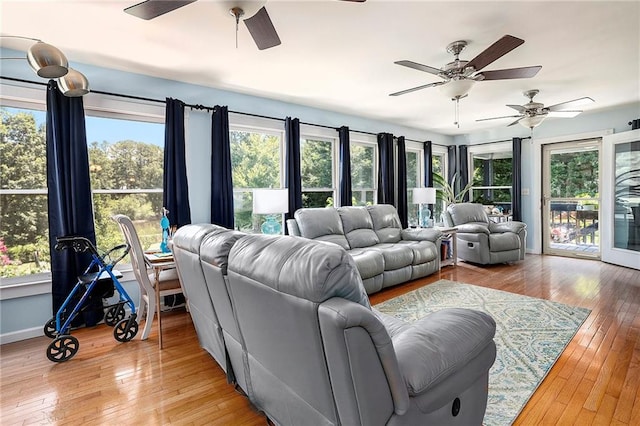 living room with light wood-type flooring, ceiling fan, and a wealth of natural light