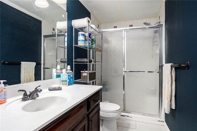 bathroom with a shower with door, vanity, tile patterned flooring, and toilet