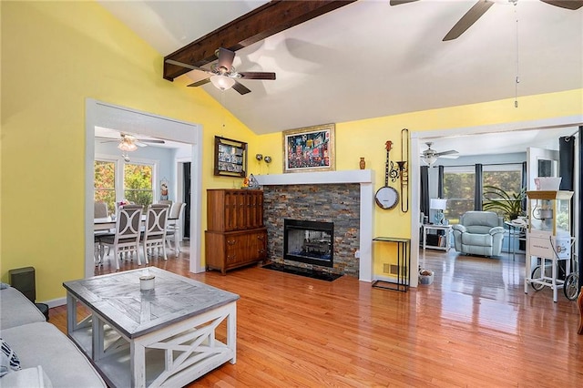 living room with ceiling fan, wood-type flooring, vaulted ceiling with beams, and a healthy amount of sunlight