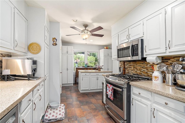 kitchen with ceiling fan, dark tile patterned floors, appliances with stainless steel finishes, white cabinets, and backsplash