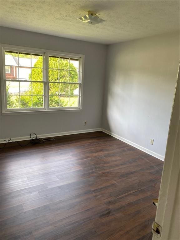 spare room featuring a textured ceiling and dark hardwood / wood-style floors