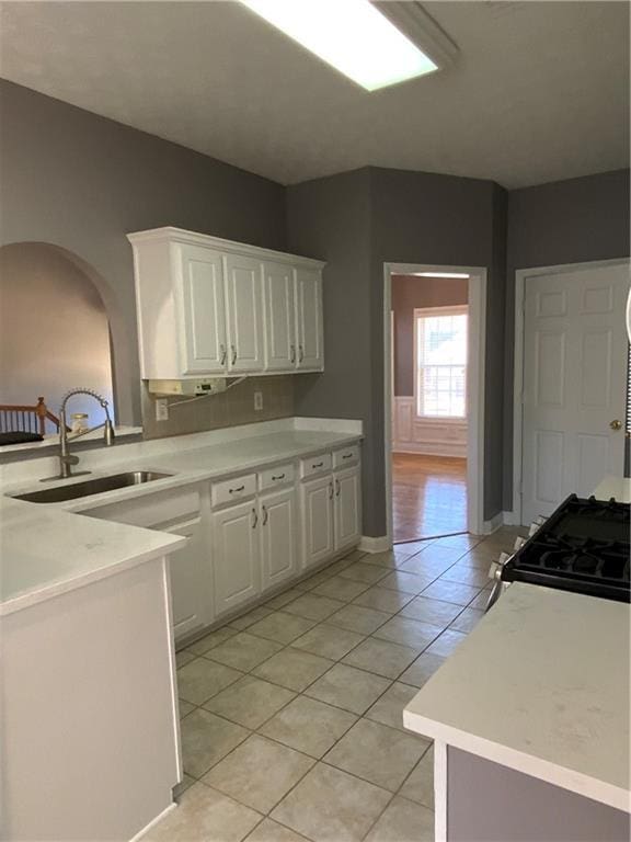 kitchen with white cabinets, light tile patterned flooring, stove, and sink