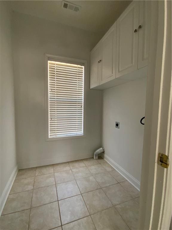 laundry room featuring electric dryer hookup, cabinets, and light tile patterned floors