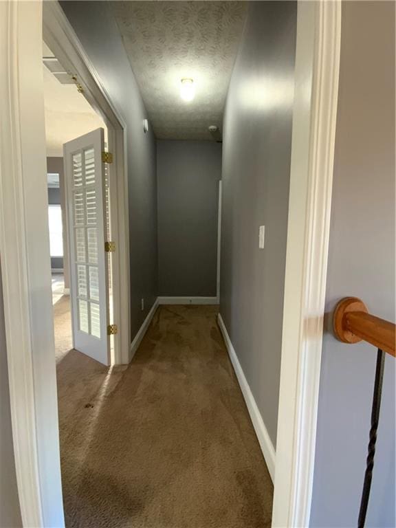 hallway with a textured ceiling and carpet flooring