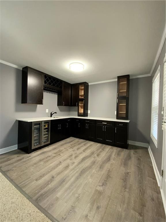 kitchen featuring sink, light hardwood / wood-style flooring, ornamental molding, and beverage cooler