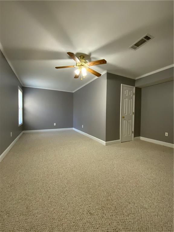 empty room featuring crown molding, carpet floors, and ceiling fan