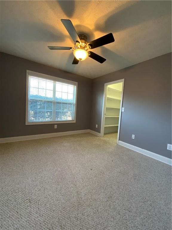 carpeted spare room featuring ceiling fan