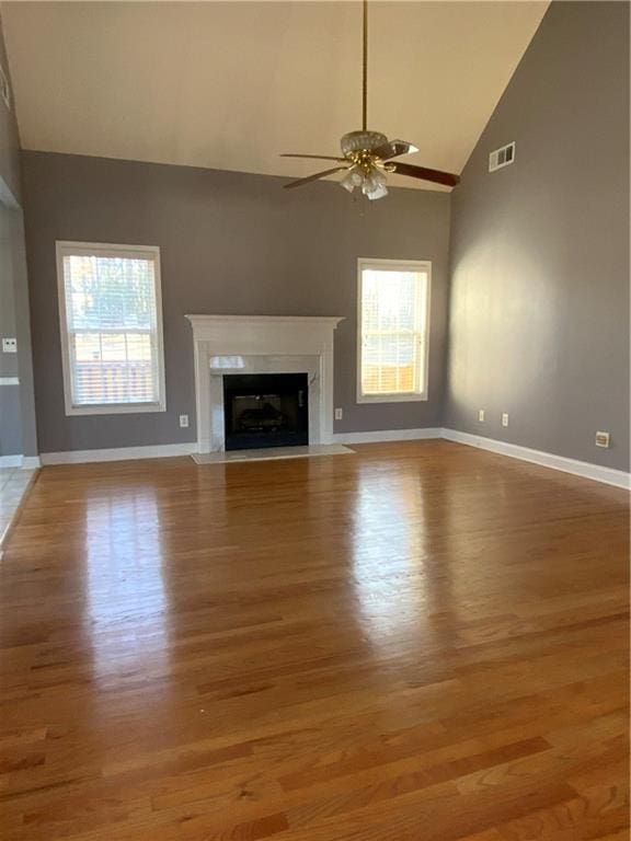 unfurnished living room with a fireplace, light hardwood / wood-style floors, ceiling fan, and a healthy amount of sunlight