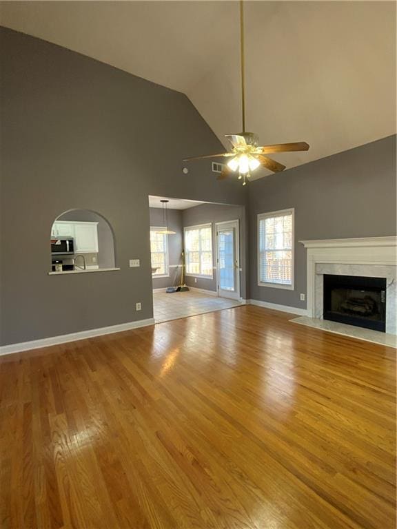 unfurnished living room featuring ceiling fan, light wood-type flooring, a premium fireplace, and vaulted ceiling