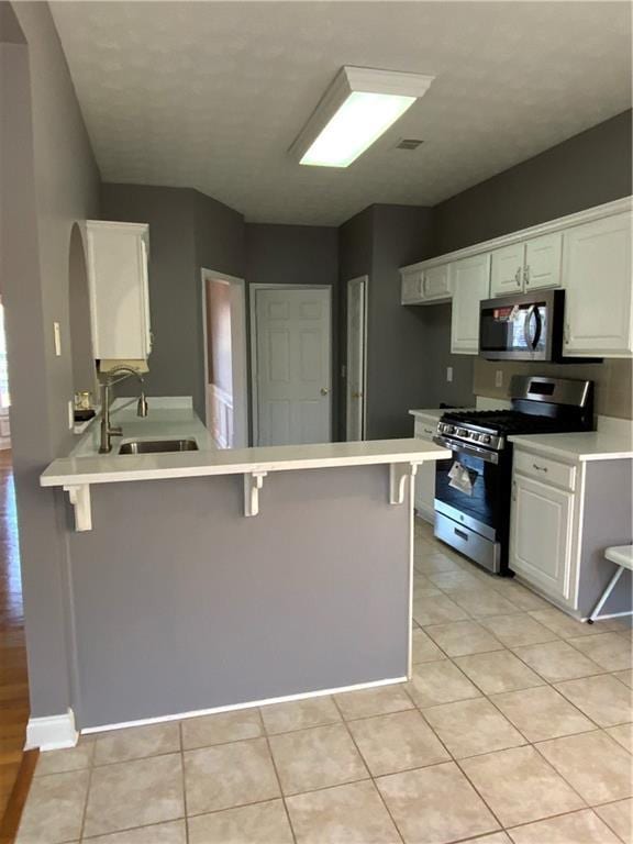 kitchen with a kitchen breakfast bar, sink, white cabinets, and stainless steel appliances