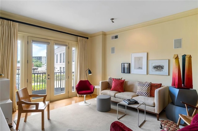 living room featuring french doors, ornamental molding, and light wood-type flooring