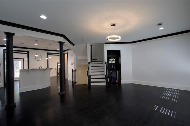 2767 Durham Dr NE, Atlanta, GA 30319 - unfurnished living room featuring ornate columns, baseboards, dark wood-type flooring, ornamental molding, and stairs