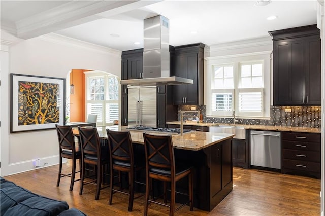 kitchen featuring sink, island exhaust hood, a center island, light stone counters, and stainless steel appliances