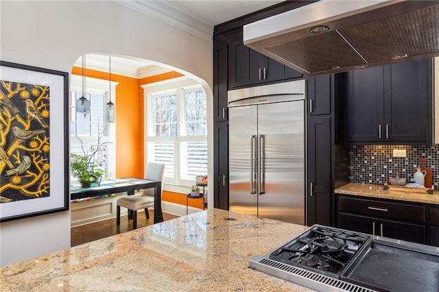 kitchen with crown molding, built in refrigerator, ventilation hood, pendant lighting, and decorative backsplash