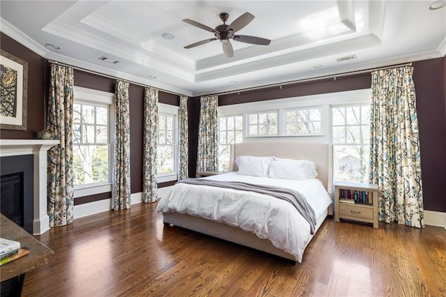 bedroom featuring crown molding, a tray ceiling, dark hardwood / wood-style floors, and ceiling fan