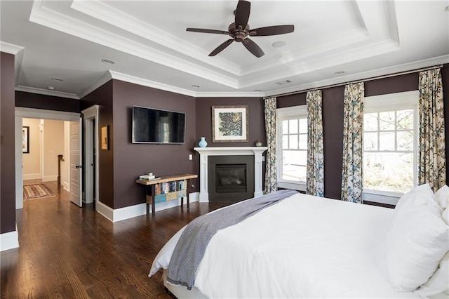 bedroom with dark hardwood / wood-style flooring, crown molding, a raised ceiling, and ceiling fan